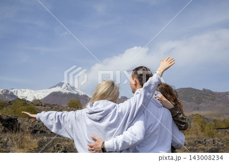 Back view of family standing with open arms and enjoying of the dramatic volcanic landscape of Mount Etna. Concept of freedom, adventure and connection with nature. 143008234