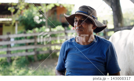 Latino stableman working with horse on ranch Latino stableman working with horse on ranch 143008317