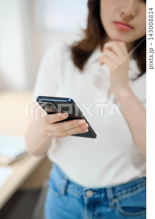 スマートフォンを持つオフィスカジュアルの若い女性 143008814