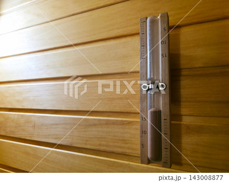 Wooden hourglass hanging on light wooden sauna wall Wooden hourglass hanging on light wooden sauna wall 143008877