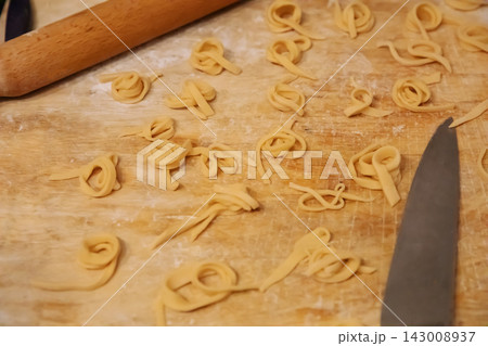 Top view of homemade noodles and knife on wooden board Top view of homemade noodles and knife on wooden board 143008937