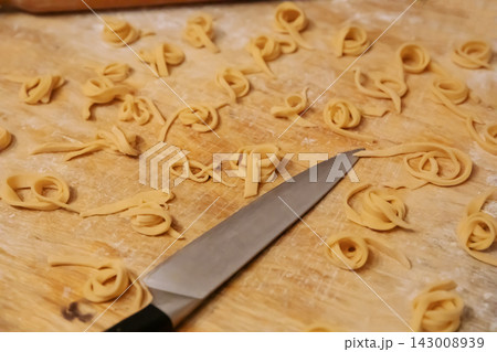 Top view of homemade noodles and knife on wooden board Top view of homemade noodles and knife on wooden board 143008939