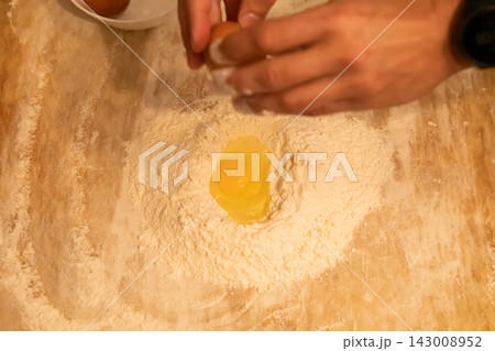 Raw egg yolk in well of flour for pasta dough Raw egg yolk in well of flour for pasta dough 143008952