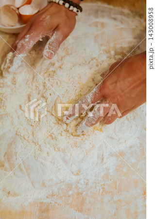 Hands mixing egg and flour into pasta dough top view 143008958