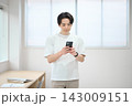 スマートフォンを持つオフィスカジュアルの若い男性 143009151