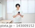 スマートフォンを持つオフィスカジュアルの若い男性 143009152