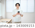 スマートフォンを持つオフィスカジュアルの若い男性 143009153