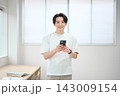 スマートフォンを持つオフィスカジュアルの若い男性 143009154