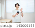 スマートフォンを持つオフィスカジュアルの若い男性 143009155