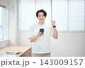 スマートフォンを持つオフィスカジュアルの若い男性 143009157