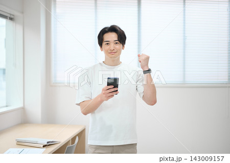 スマートフォンを持つオフィスカジュアルの若い男性 143009157