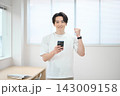 スマートフォンを持つオフィスカジュアルの若い男性 143009158