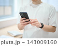 スマートフォンを持つオフィスカジュアルの若い男性 143009160