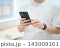 スマートフォンを持つオフィスカジュアルの若い男性 143009161