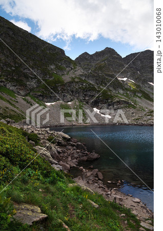 Mountain lake with rocky shore and steep cliffs 143010068
