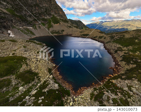 Aerial View of Alpine Lake Surrounded by Rocky Mountains Aerial View of Alpine Lake Surrounded by Rocky Mountains 143010073