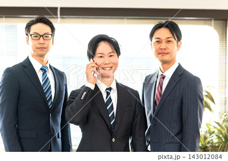 3人のスーツ姿の男性とスマホで通話するスーツ姿の男性 143012084