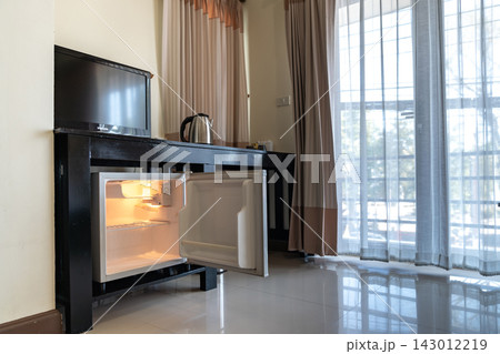 Mini refrigerator, wooden cabinet, and open wardrobe create a simple room layout focused on storage, practical furniture, and everyday accommodation use. 143012219