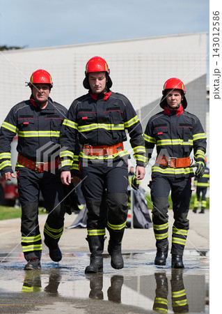 Firefighters Walking In Uniform With Red Helmets Responding As A Team During Emergency Training Exercise 143012586