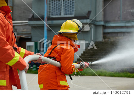 Firefighters Training With Hose Spraying Water During Urban Firefighting Drill And Safety Exercise 143012791