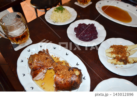 Traditional czech roasted duck with dumplings red cabbage and beer served on plates for restaurant menu and food background use Traditional czech roasted duck with dumplings red cabbage and beer served on plates for restaurant menu and food background use 143012896
