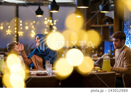 Family Dinner Celebration In Restaurant With Mother Wearing Hijab And Father And Son Family Dinner Celebration In Restaurant With Mother Wearing Hijab And Father And Son 143012989