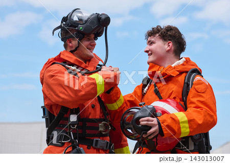 Two Firefighters In Orange Protective Gear Sharing A Handshake After Search And Rescue Training Exercise 143013007