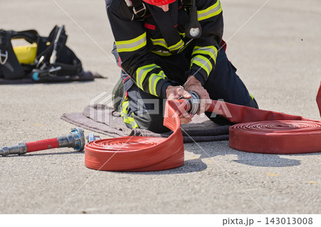 Firefighter Connecting Red Fire Hose During Training Drill With Protective Gear and Safety Equipment Firefighter Connecting Red Fire Hose During Training Drill With Protective Gear and Safety Equipment 143013008