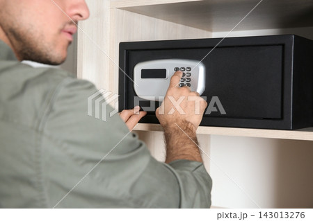 Man opening black steel safe with electronic lock at hotel, closeup Man opening black steel safe with electronic lock at hotel, closeup 143013276