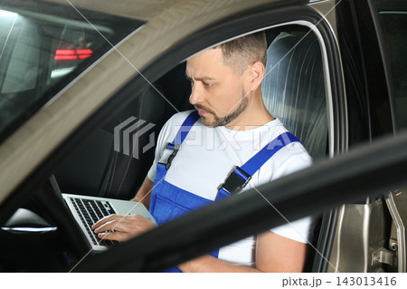 Mechanic with laptop doing car diagnostic at automobile repair shop Mechanic with laptop doing car diagnostic at automobile repair shop 143013416