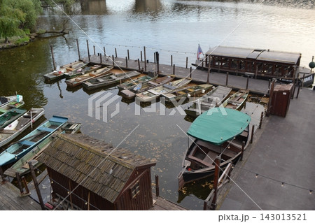 Riverside dock with multiple moored wooden boats and covered skiff for travel background and scenic landscape banner 143013521