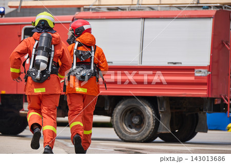 Firefighters In Orange Protective Gear Running Toward Red Fire Truck With Breathing Apparatus 143013686