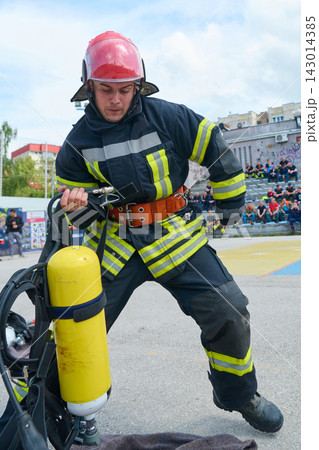 Firefighter Putting On Breathing Apparatus During Urban Training Drill With Yellow Oxygen Cylinder Firefighter Putting On Breathing Apparatus During Urban Training Drill With Yellow Oxygen Cylinder 143014385