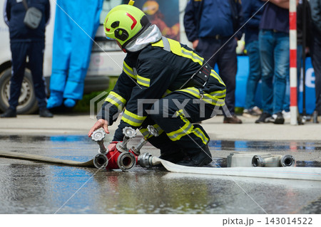 Firefighter Connecting Hose to Hydrant During Emergency Training Drill With Protective Gear and Helmet 143014522
