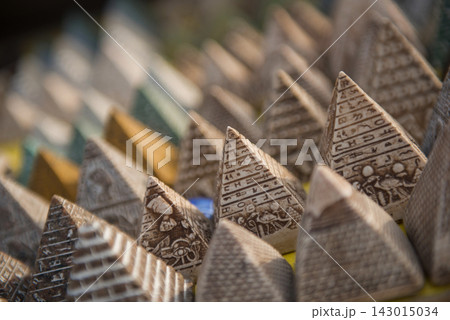Close up of handcrafted miniature pyramid souvenirs covered in hieroglyphs and deity carvings displayed in rows at an Egyptian market stall ideal for 143015034