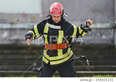 Firefighter In Full Gear With Helmet And Safety Belt Practicing Rescue Training Outdoors 143015131