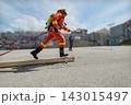 Firefighter In Full Gear Running With Hose During Outdoor Training Exercise At Urban Drill 143015497
