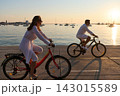 Couple Cycling Along Seaside Promenade At Sunset On Vacation For Relaxed Romantic Outdoor Leisure 143015589
