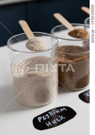 Psyllium husk powder scooped with a wooden spoon on a white studio counter for dietary fiber Psyllium husk powder scooped with a wooden spoon on a white studio counter for dietary fiber 143016088