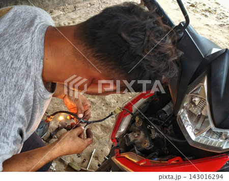 man changing wheel on a motorcycle man changing wheel on a motorcycle 143016294