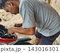 man changing wheel on a motorcycle 143016301