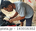 man changing wheel on a motorcycle 143016302
