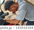man changing wheel on a motorcycle 143016304