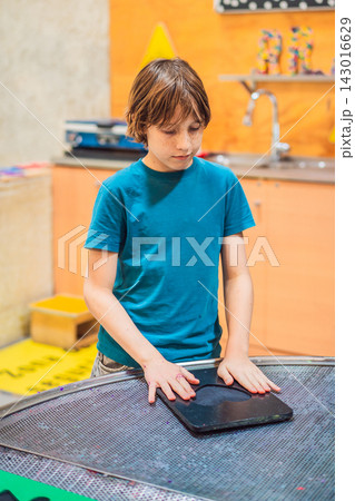 Boy experimenting with hands on science activity in a learning space indoors with interactive equipment STEM education curiosity creative play concentration and close up. Boy experimenting with hands on science activity in a learning space indoors with interactive equipment STEM education curiosity creative play concentration and close up. 143016629