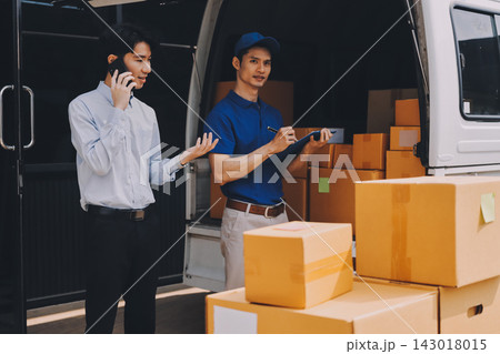 Young businessman signing a delivery receipt document on a clipboard held by a courier in a blue uniform. Young businessman signing a delivery receipt document on a clipboard held by a courier in a blue uniform. 143018015
