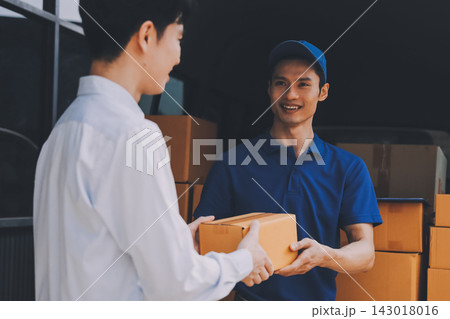 Young businessman signing a delivery receipt document on a clipboard held by a courier in a blue uniform. Young businessman signing a delivery receipt document on a clipboard held by a courier in a blue uniform. 143018016