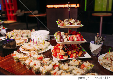 Catering buffet with assorted finger food sandwiches fruit and appetizers at a festive event Catering buffet with assorted finger food sandwiches fruit and appetizers at a festive event 143018117