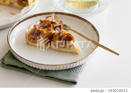 Slice of delicious fig tart served on white plate with golden rim and fork 143018211