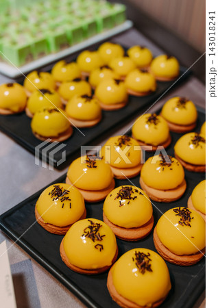 Yellow glazed pastries with chocolate sprinkles on black trays 143018241