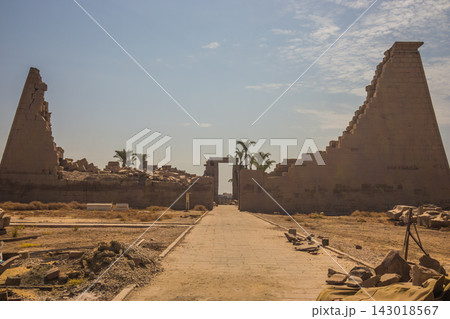 Ancient Egyptian temple ruins with stone pylon and pathway 143018567